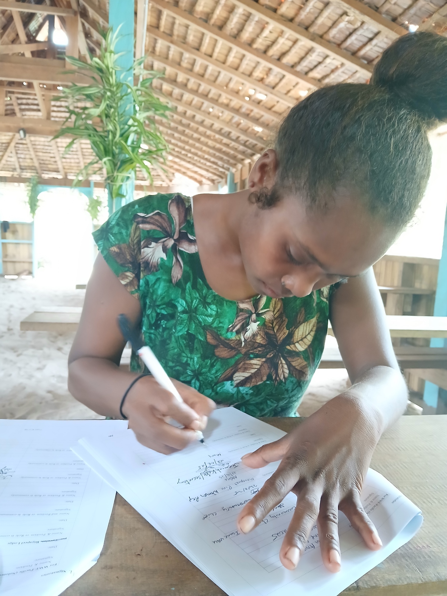 A youth Representative, Mary Tovongo, signing the community agreement at Rigapeel lodge, Tavulea community, Small Ngella, Central Province.